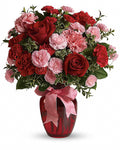 Bouquet of red and pink flowers in a red vase with a pink ribbon 