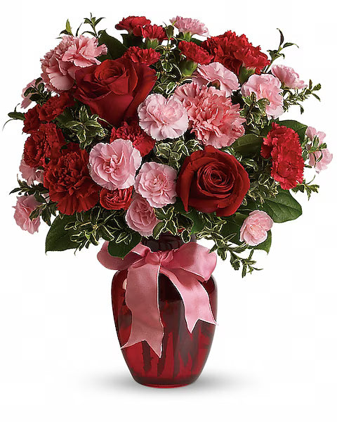 Bouquet of red and pink flowers in a red vase with a pink ribbon 