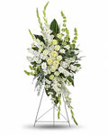 A large floral arrangement in a tall metal stand, featuring white and pale yellow flowers with green foliage, photographed on a clean white background.