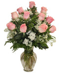 Bouquet of pink roses with green leaves and white flowers in a clear vase