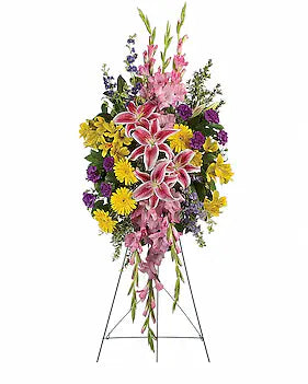 A large floral arrangement in a three-tier balloon style on a metal stand, featuring pink lilies, yellow daisies, purple flowers, and green foliage, isolated on a white background.